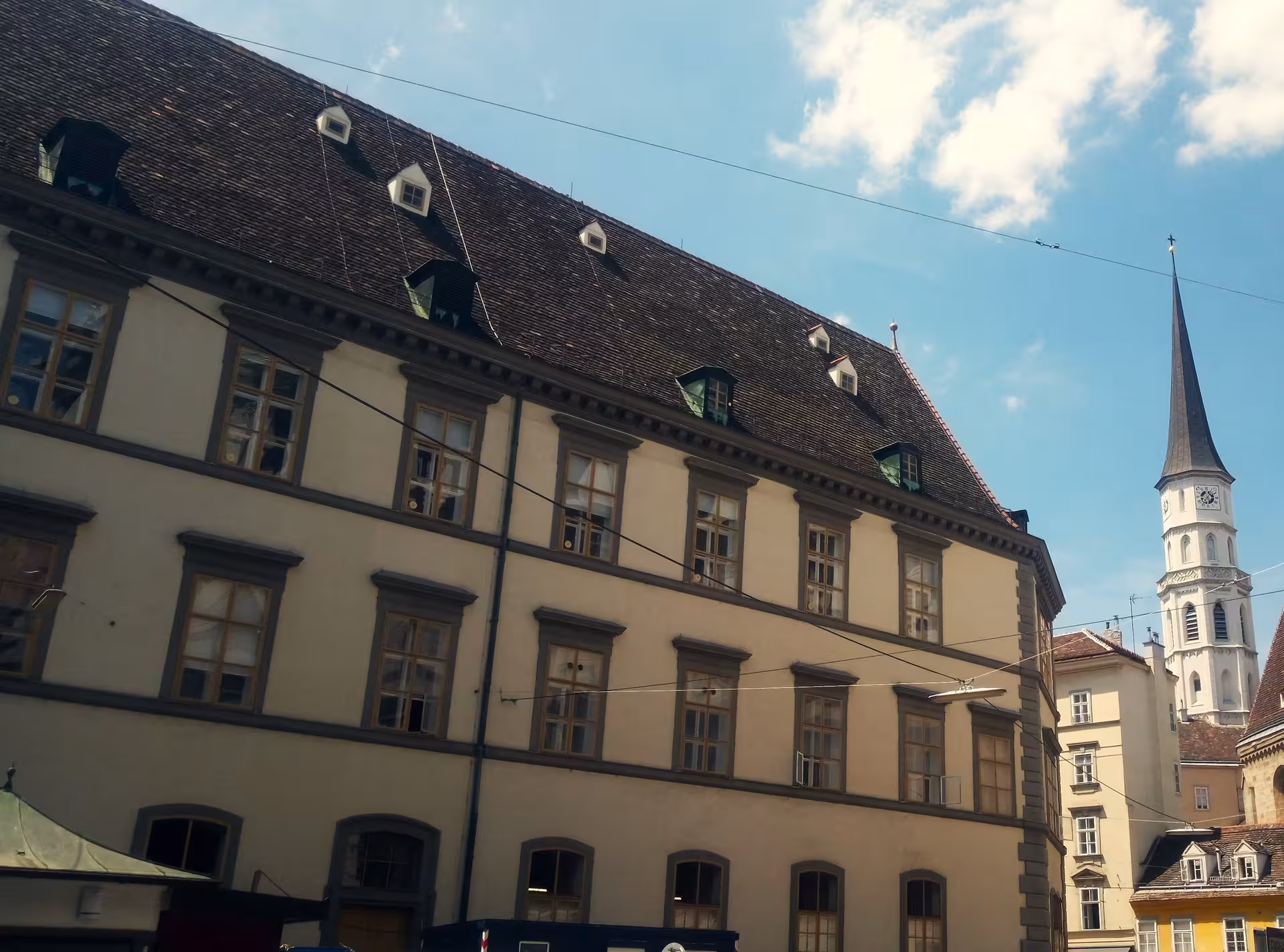 Quiet Vienna backstreet with historic rooftops and church spire, featured on the Secret Vienna 3-hour tour