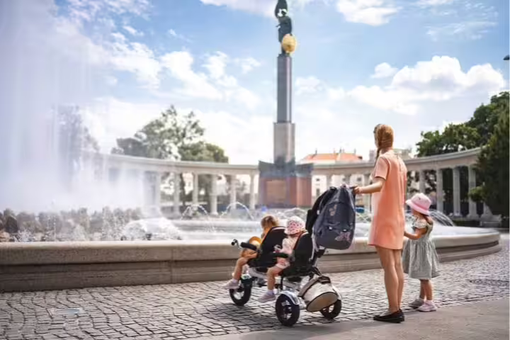 Family enjoying Vienna's city highlights at a scenic fountain, perfect for a private tour with museum visits and cake tasting.