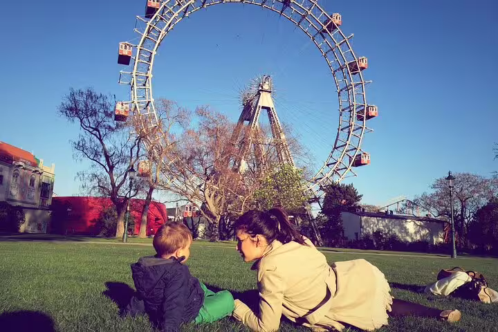 Family enjoying a sunny day at Vienna's Prater Park, with the iconic Ferris wheel in the background, perfect for a family-friendly tour.