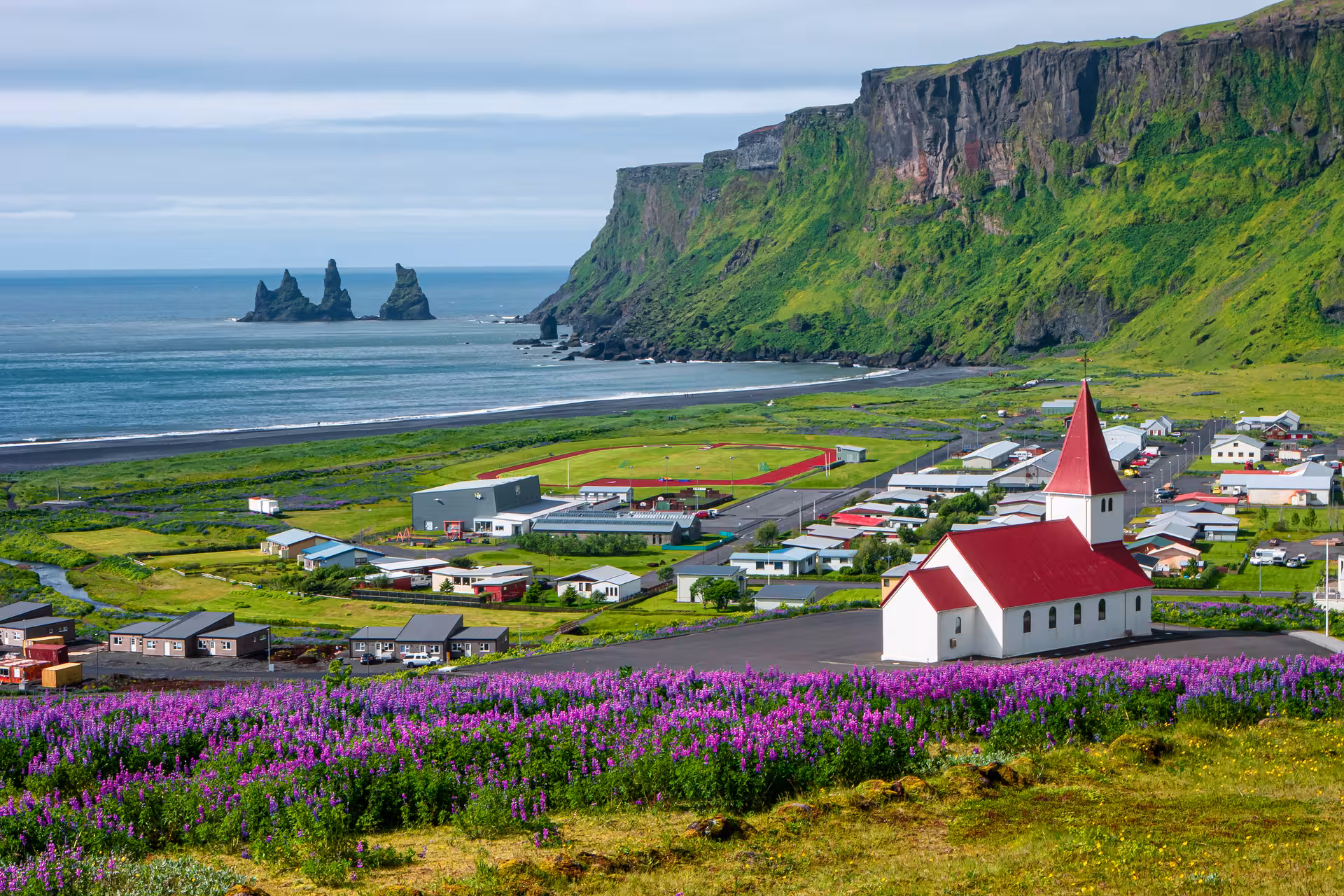 Scenic view of Vik village with iconic black sand beach and Reynisdrangar sea stacks in South Iceland.