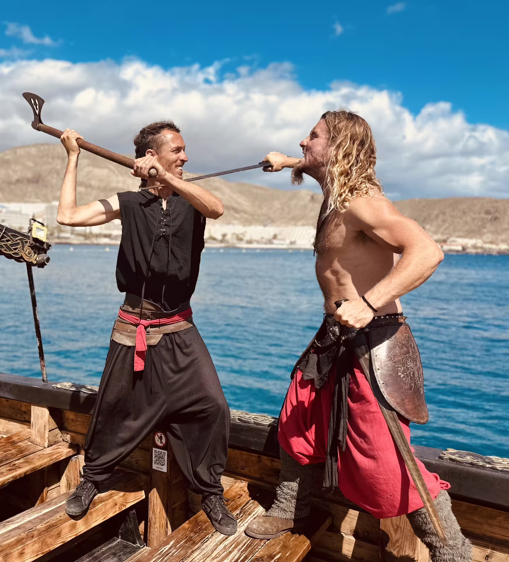 Viking reenactors duel with axes on deck during the 3h Viking Cruise, showcasing immersive entertainment at sea.