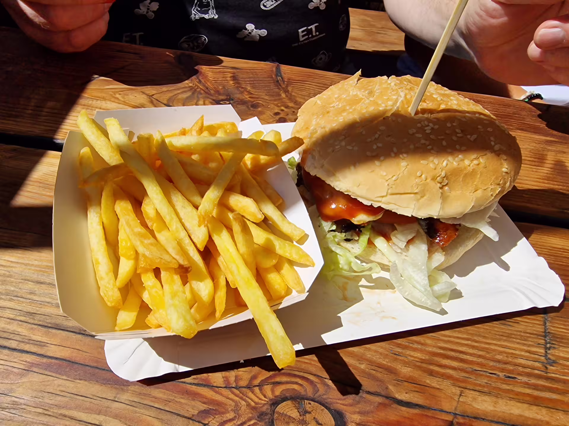 A delicious meal of a juicy burger with fresh lettuce and crispy fries on a wooden table, ideal for dining on a Viking cruise.