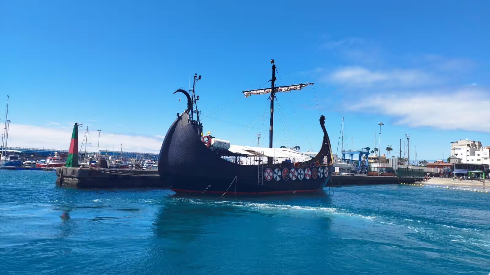 A Viking-style ship docked at a vibrant marina under a clear blue sky, perfect for a 3-hour cruise with swimming.