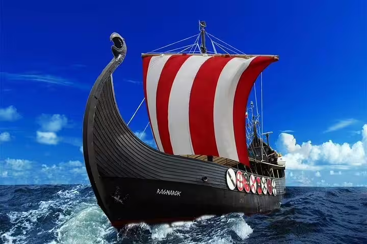 Majestic Viking ship with red and white sail on a Viking Cruise for whale and dolphin watching against clear blue skies.