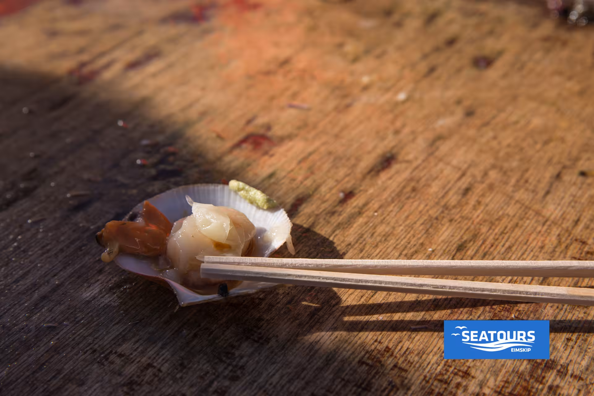 Fresh scallop sushi served in shell with chopsticks during Viking Sushi Tour, Icelandic seafood tasting at sea