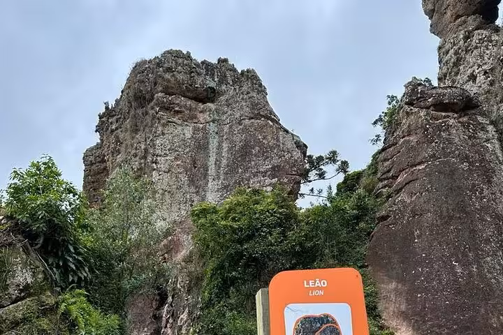 Towering rock formations and lush greenery at Vila Velha Park with a sign marking the Lion's Rock attraction.