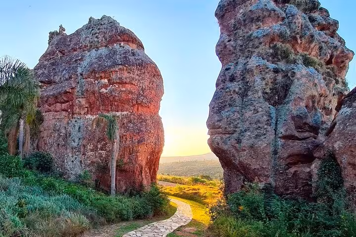 Sunlit path between towering rock formations at Vila Velha State Park, offering scenic hiking opportunities.