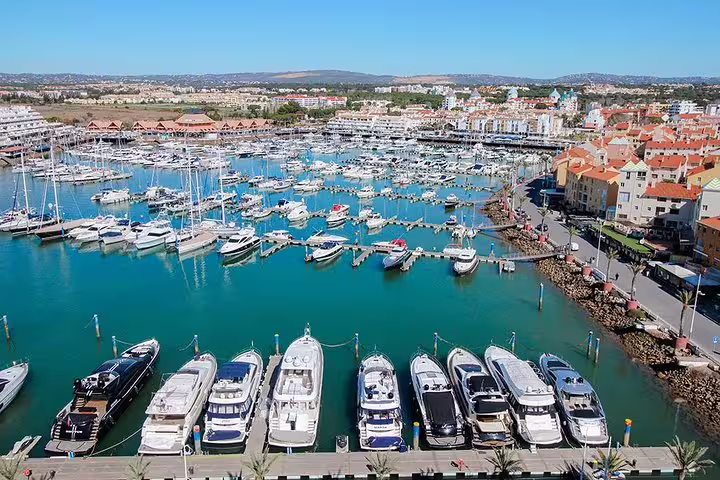 Scenic view of Vilamoura Marina in the Algarve, showcasing luxury yachts and vibrant coastal architecture under a clear sky.