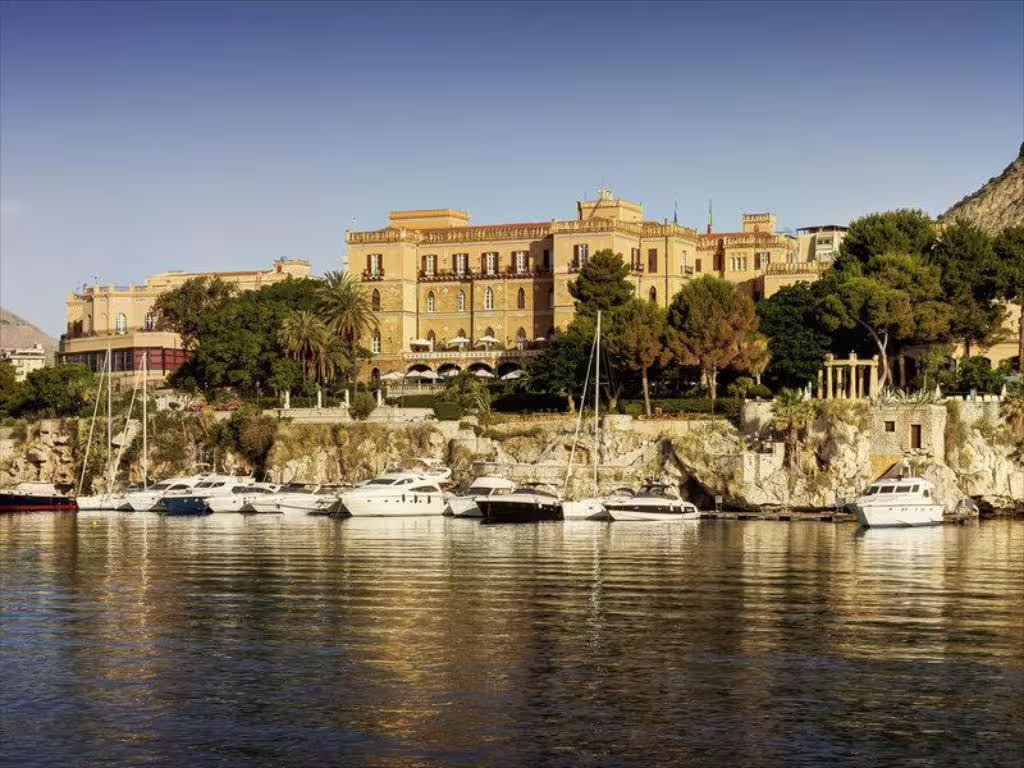 Waterfront view of Villa Igiea Rocco Forte Palermo with luxury yachts moored along the Sicilian coastline