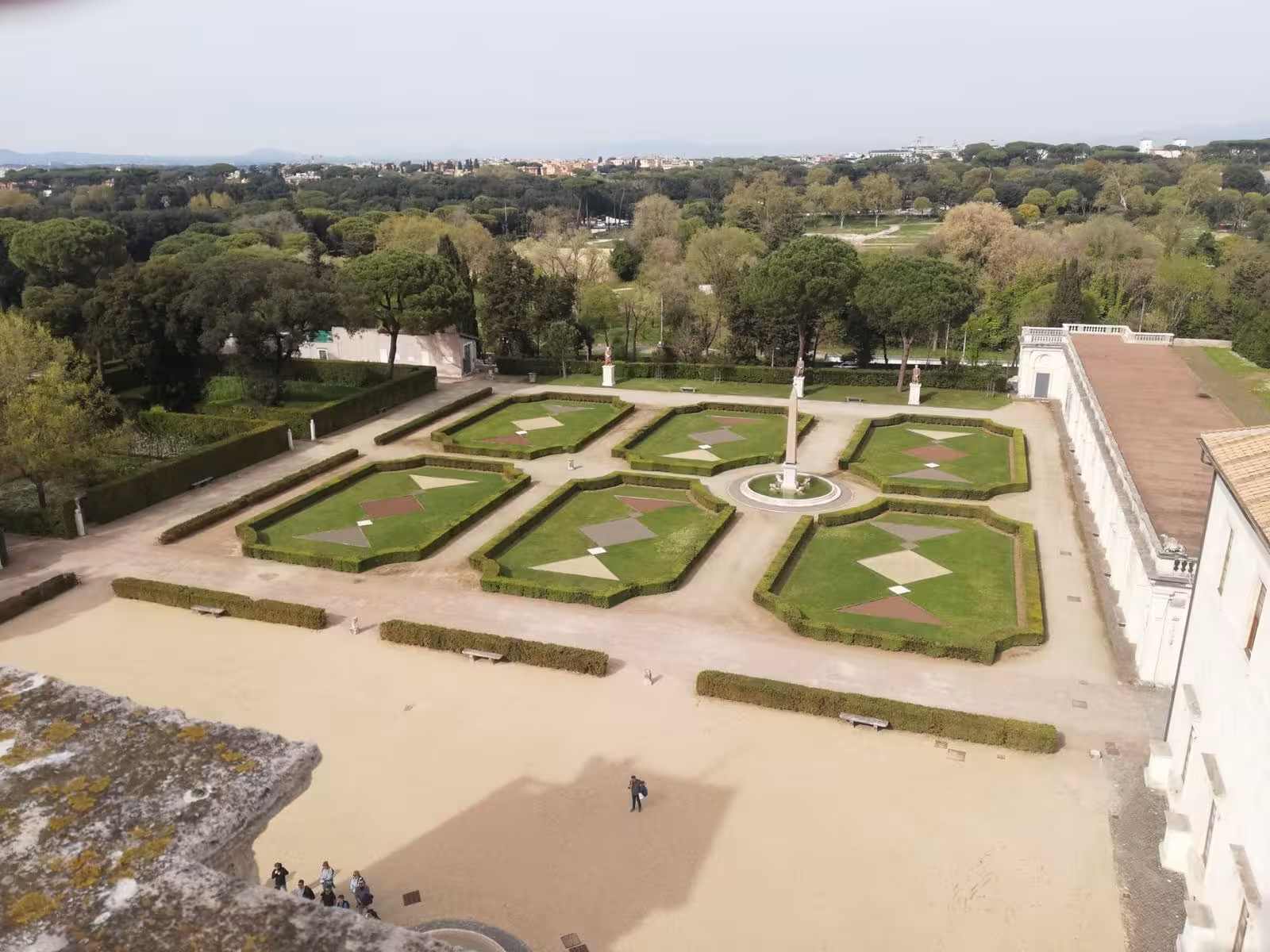 Aerial view of Villa Medici's elegant geometric gardens surrounded by lush trees in Rome, perfect for a scenic tour.