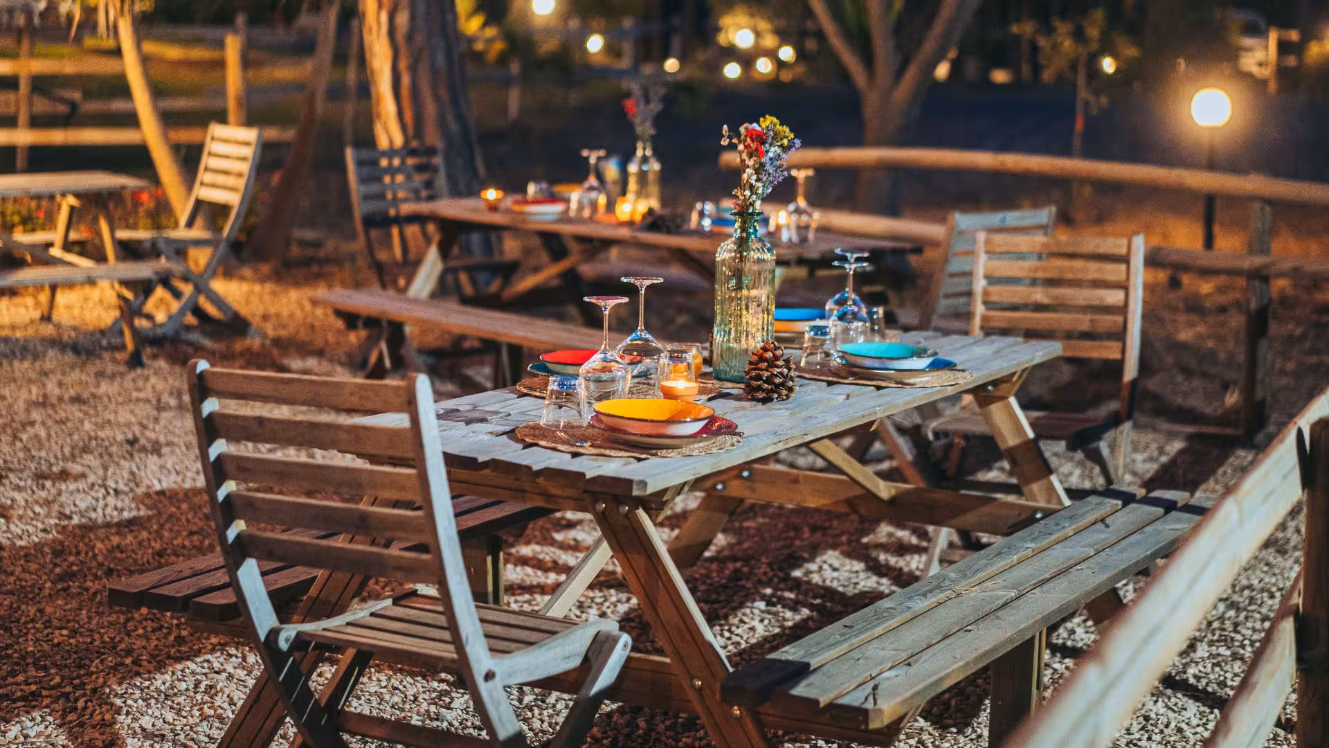 Charming outdoor dining setup in a villa garden with rustic wooden tables set for a relaxing afternoon meal.