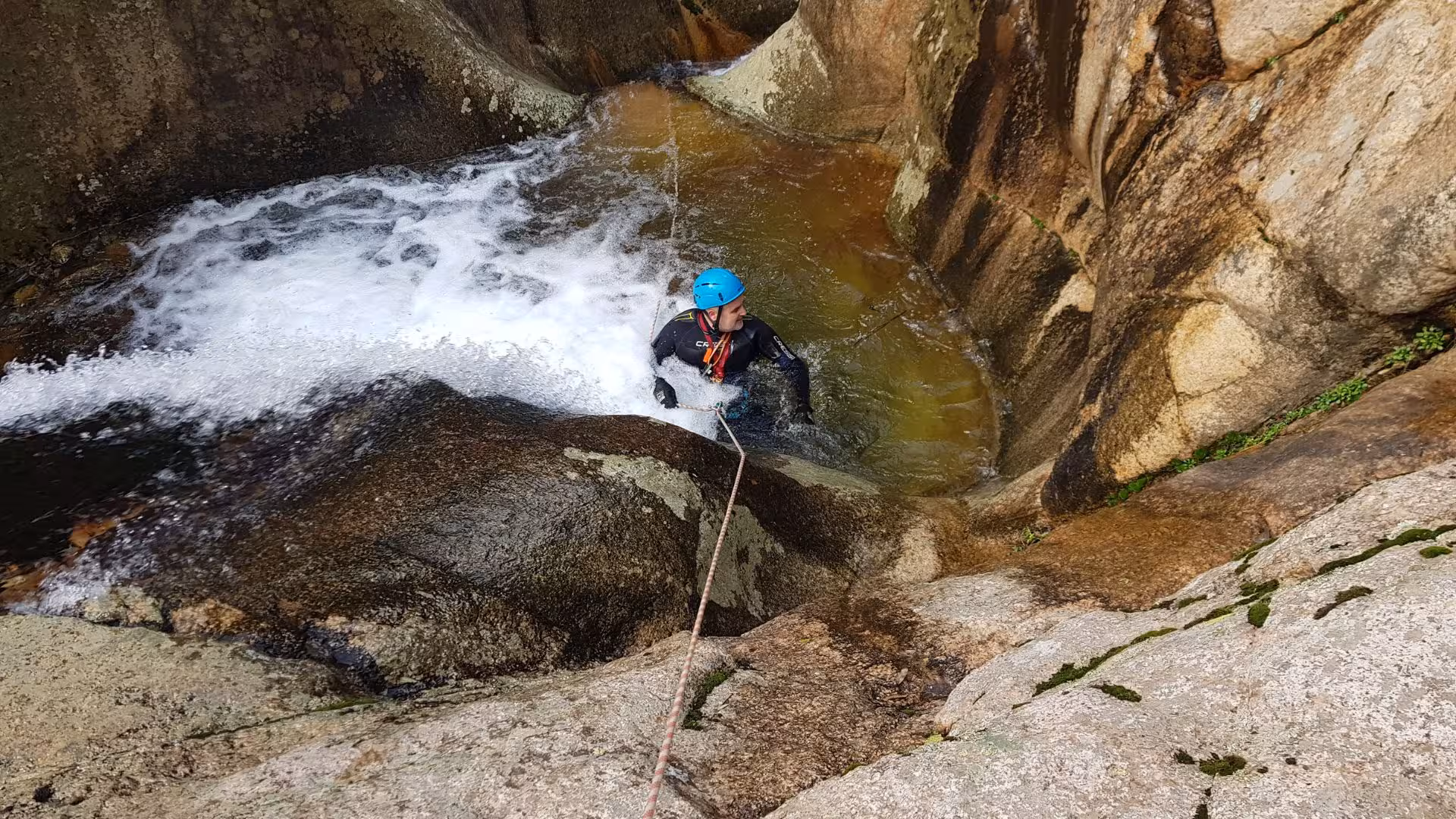 Adventurer in helmet and wetsuit canyoning through rocky waters of Rio Zairi, Villacidro, Sardinia.