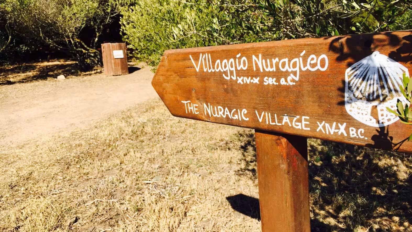Wooden sign pointing to Villaggio Nuragico, an ancient Nuragic village, in the archaeological area of Santa Teresa Gallura.