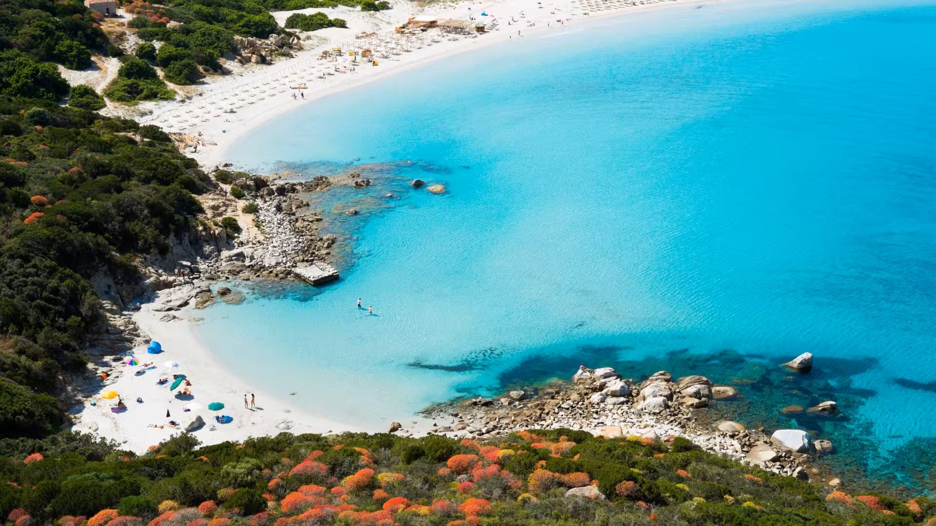 Aerial view of Villasimius beach with crystal-clear turquoise waters and lush green shoreline, perfect for a dinghy tour.