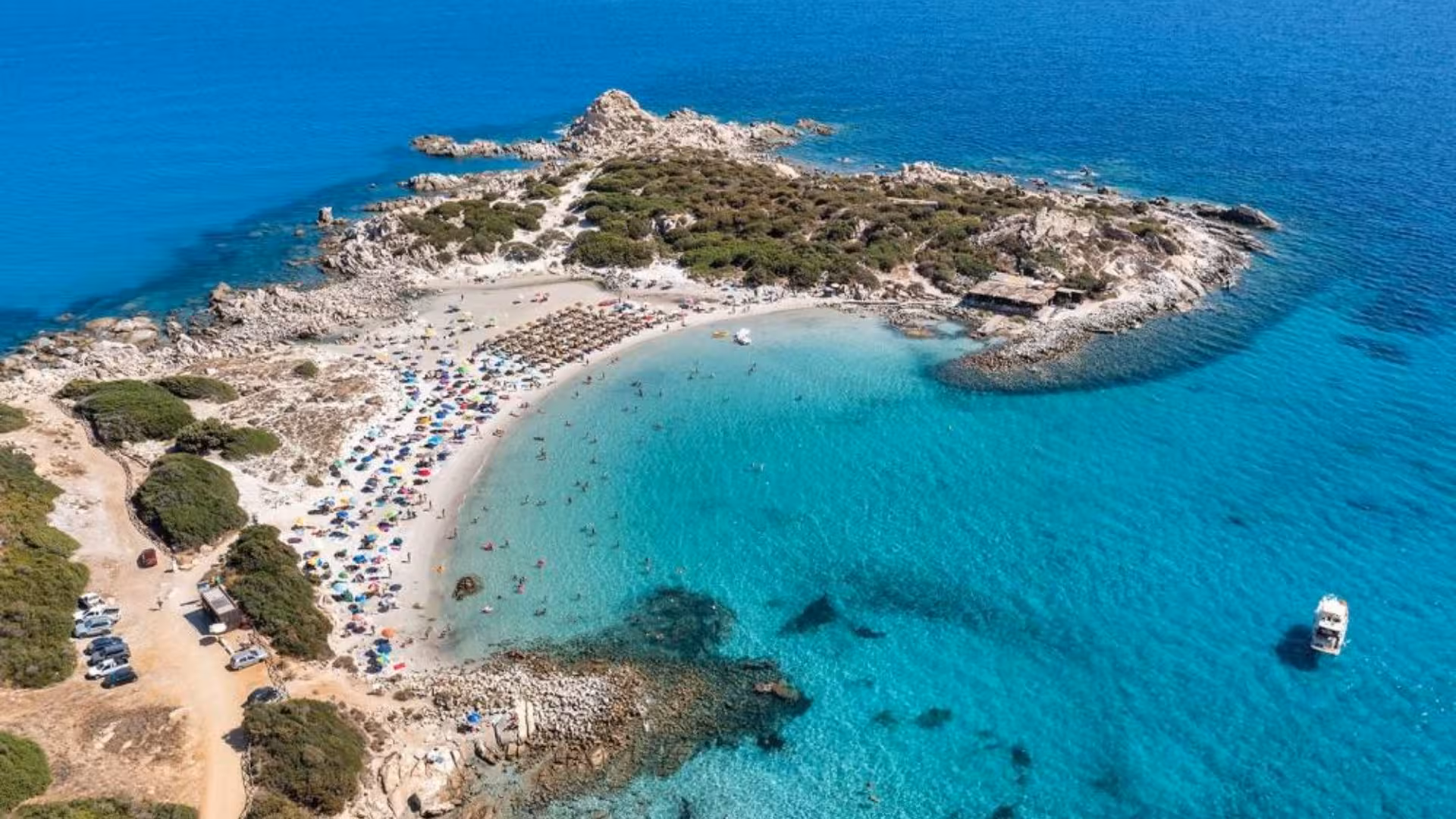Aerial view of Villasimius beach with crystal-clear waters and a dinghy, ideal for a scenic coastal tour.