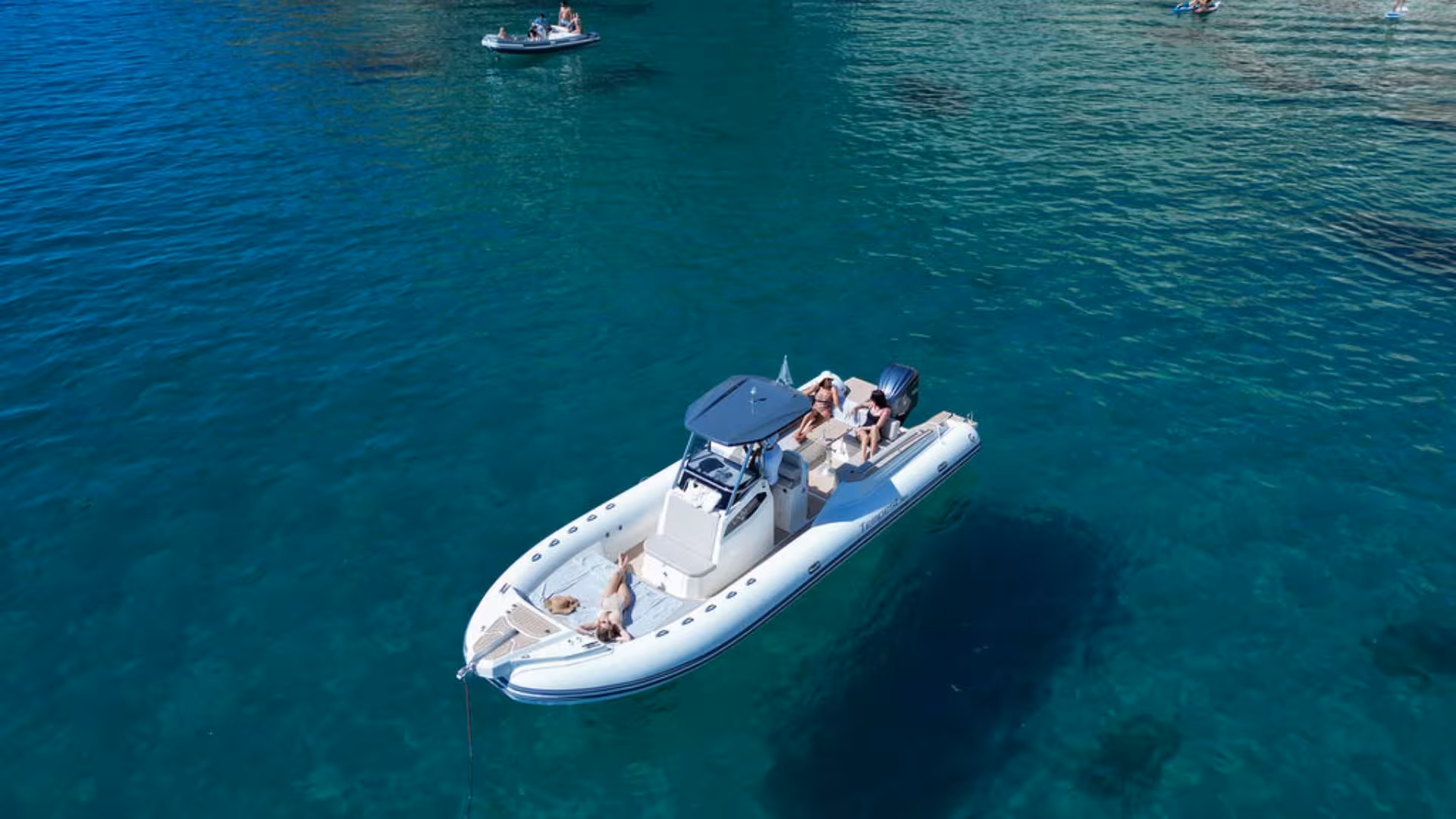 Aerial view of a dinghy with passengers enjoying a Villasimius tour on crystal-clear Mediterranean waters.