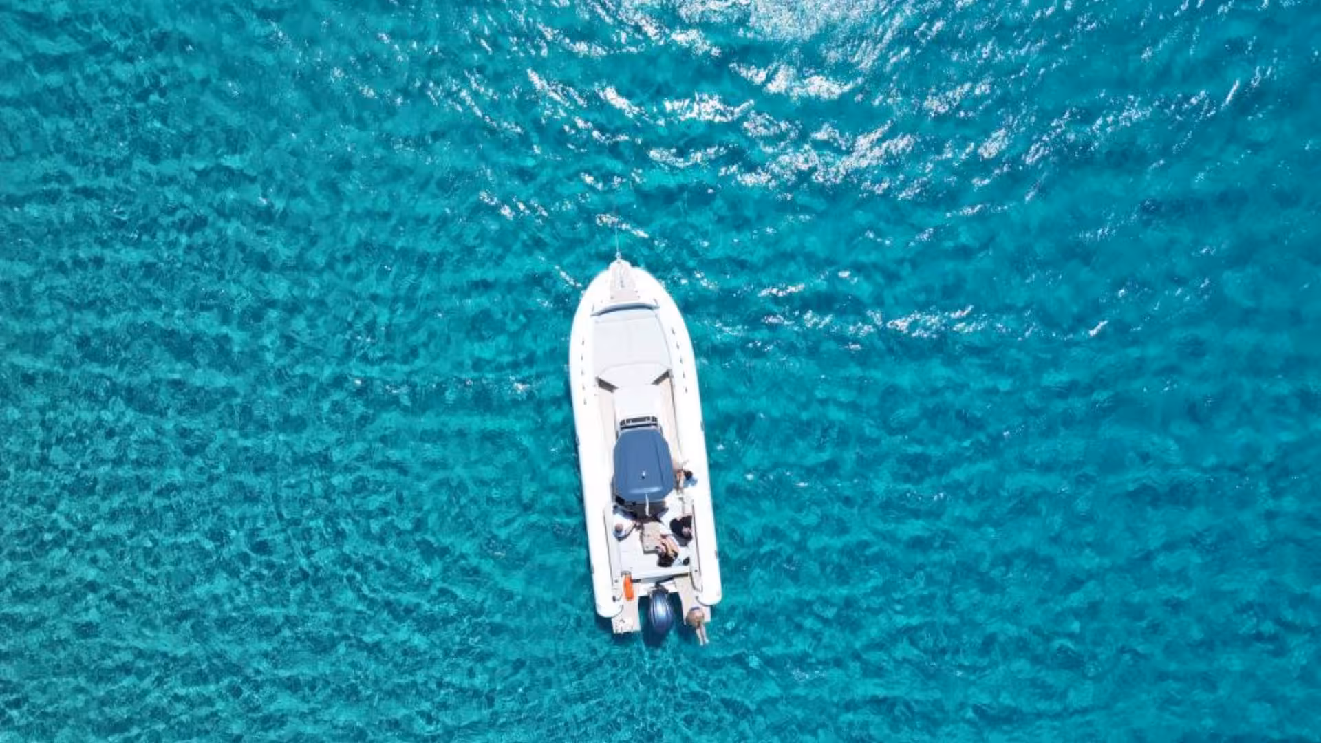 Top-down shot of a dinghy cruising through the sparkling blue waters of Villasimius, perfect for a scenic tour.
