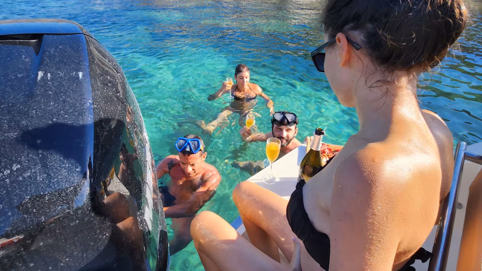Experience snorkeling and celebration on a Villasimius private boat tour, with guests enjoying drinks in crystal-clear waters.