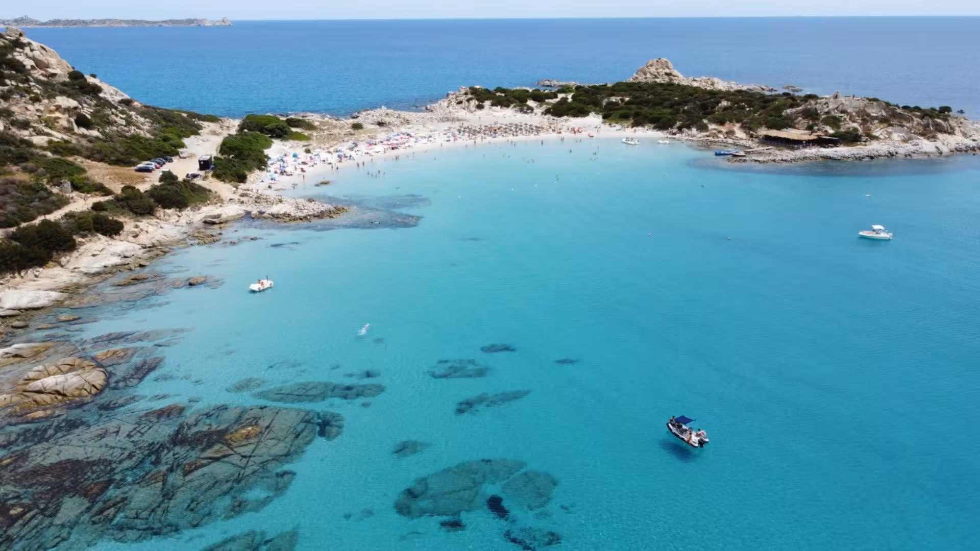 Stunning turquoise bay in Villasimius with sandy beaches and boats, perfect for a private boat tour adventure.