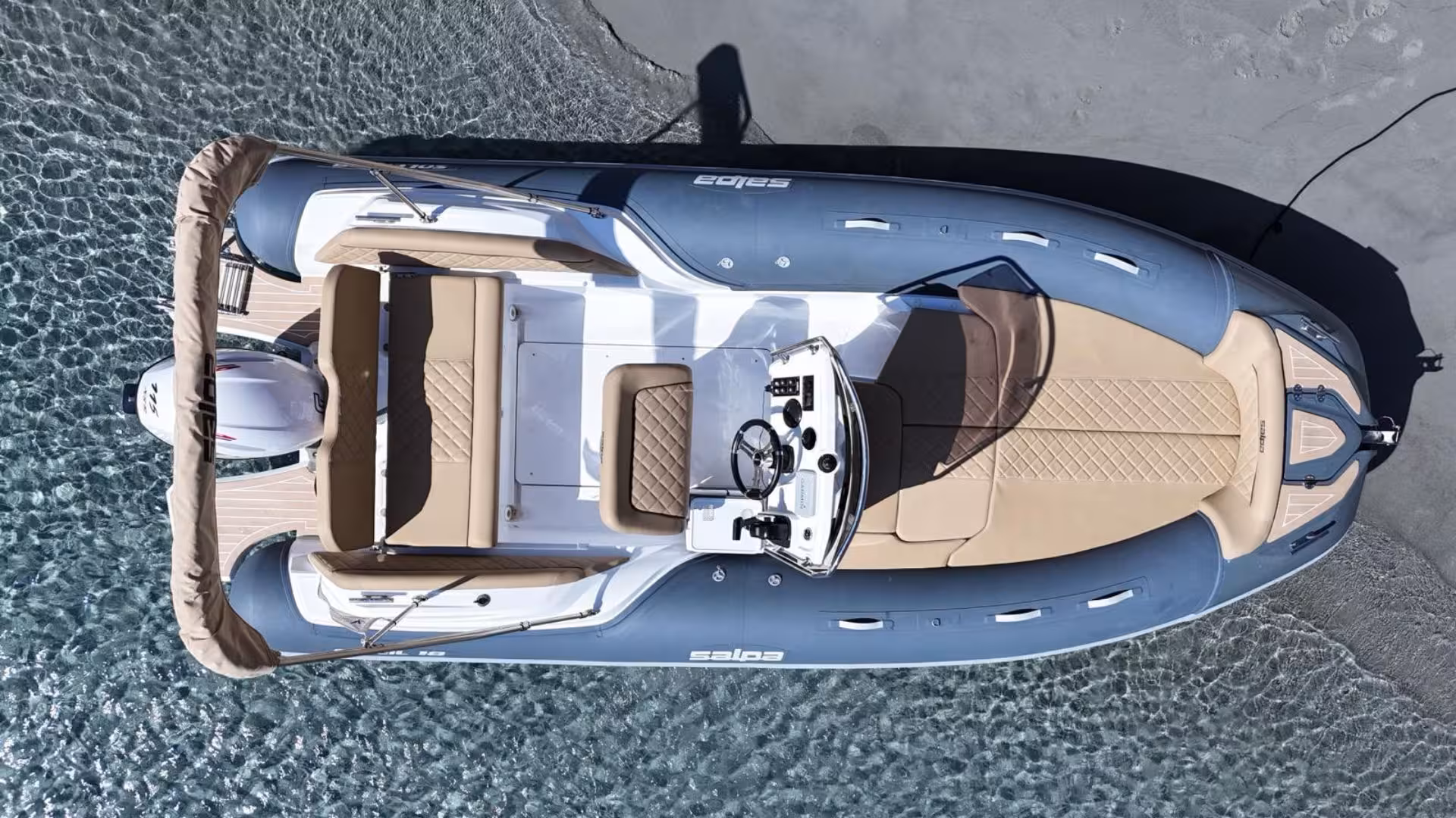 Bird's-eye view of a luxurious dinghy ready for a private tour in Villasimius, showcasing sleek design and clear waters.