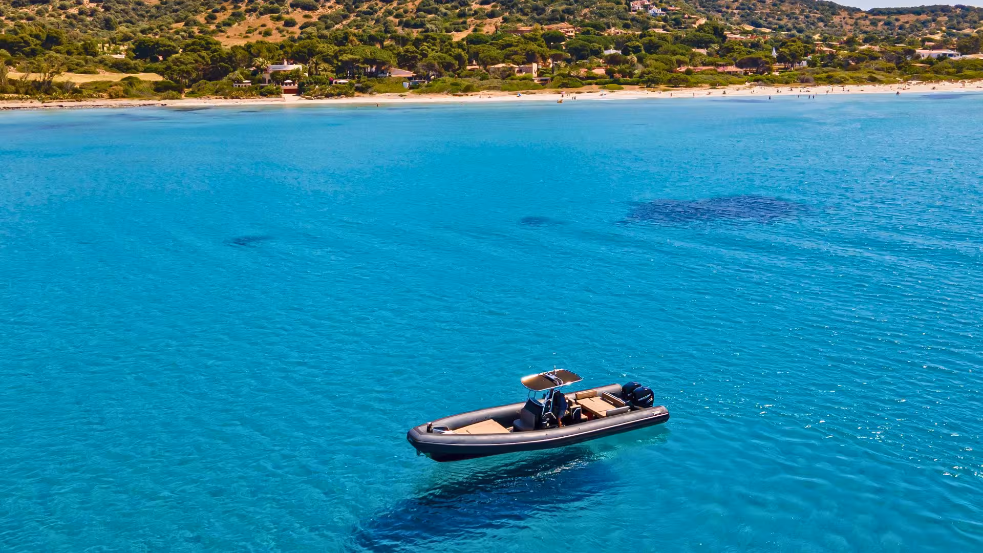RIB boat floating on serene blue waters near the scenic beaches and lush hills of Villasimius, perfect for snorkeling.
