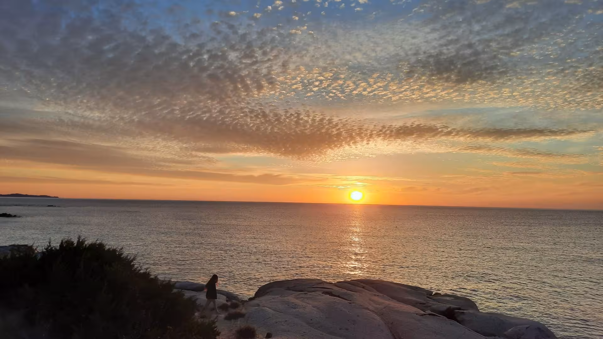 Dramatic sunset over the sea with rocky cliffs in Villasimius, perfect for a tranquil evening boat tour.