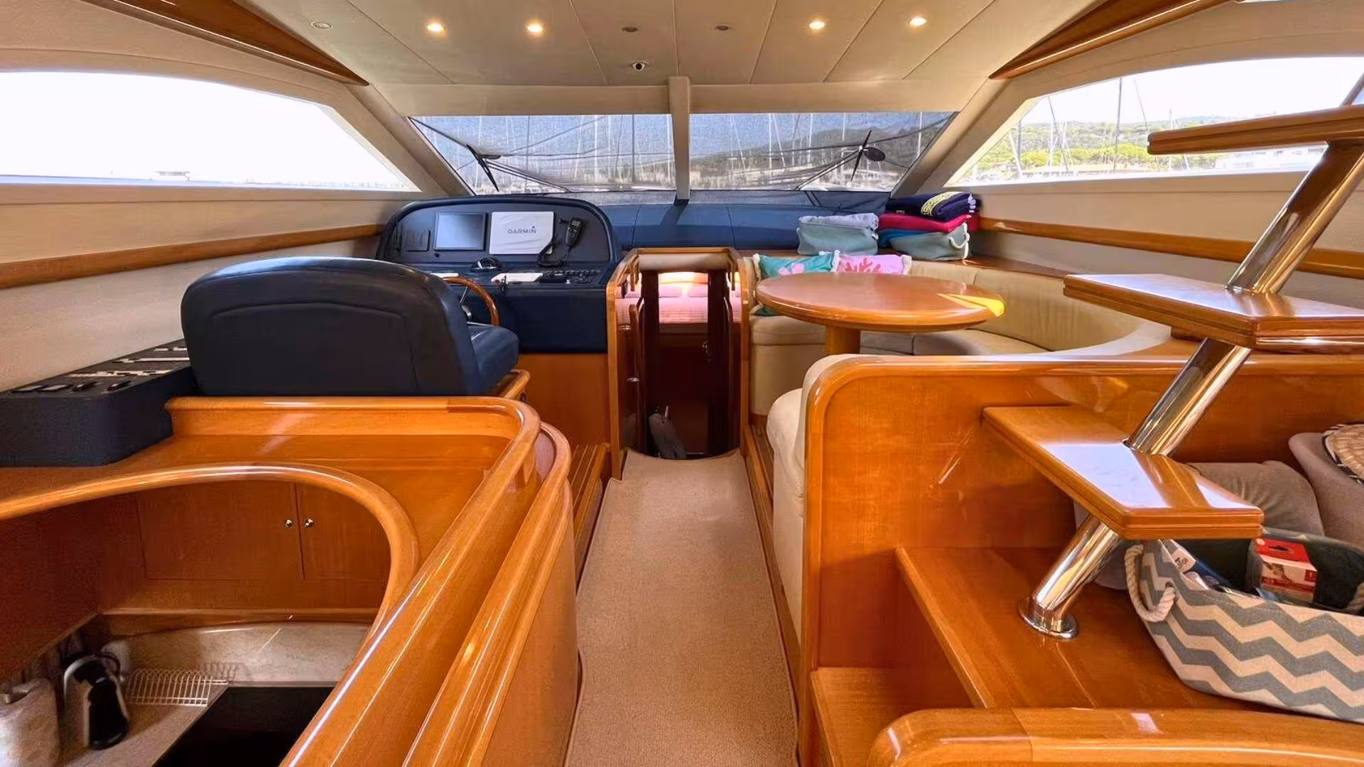 Elegant yacht interior in Villasimius featuring a cozy seating area, control panel, and wooden finishes.