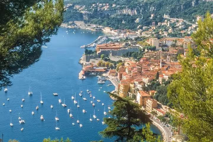 Scenic coastline of Villefranche-sur-Mer with sailboats on the azure waters during the French Riviera guided tour.