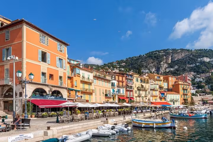 Charming waterfront cafes and colorful buildings line the picturesque dock in Villefranche-sur-Mer, perfect for a private tour.
