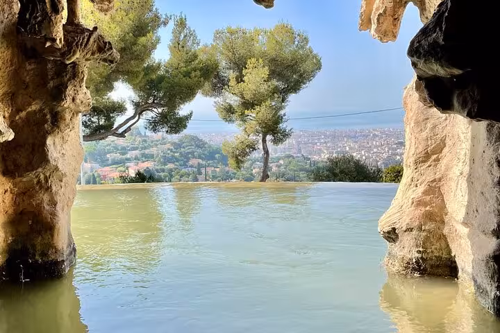 Scenic Villefranche-sur-Mer landscape from a cave with picturesque tree and city views, perfect for a tranquil tour moment.