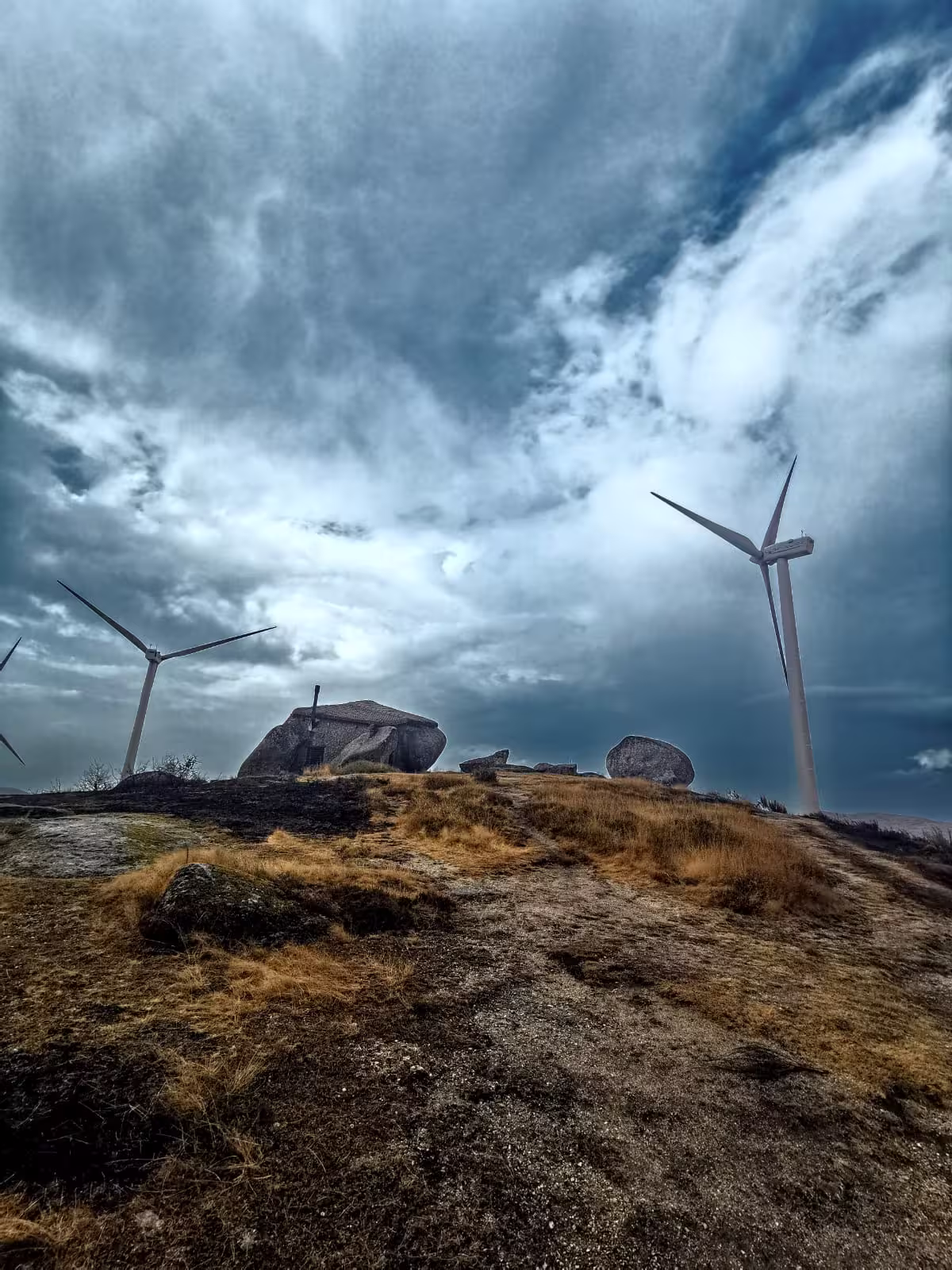 Wind turbines against a dramatic sky in Vinho Verde region, highlighting sustainable energy on a Portugal wine tour.