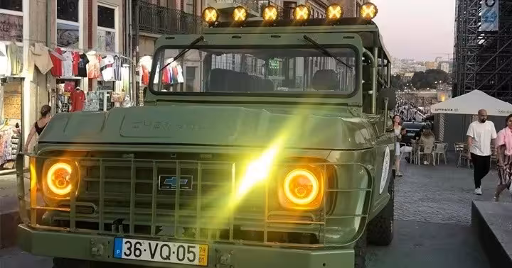 Vintage 4x4 with glowing headlights on Porto evening streets, part of Douro River romance night tour