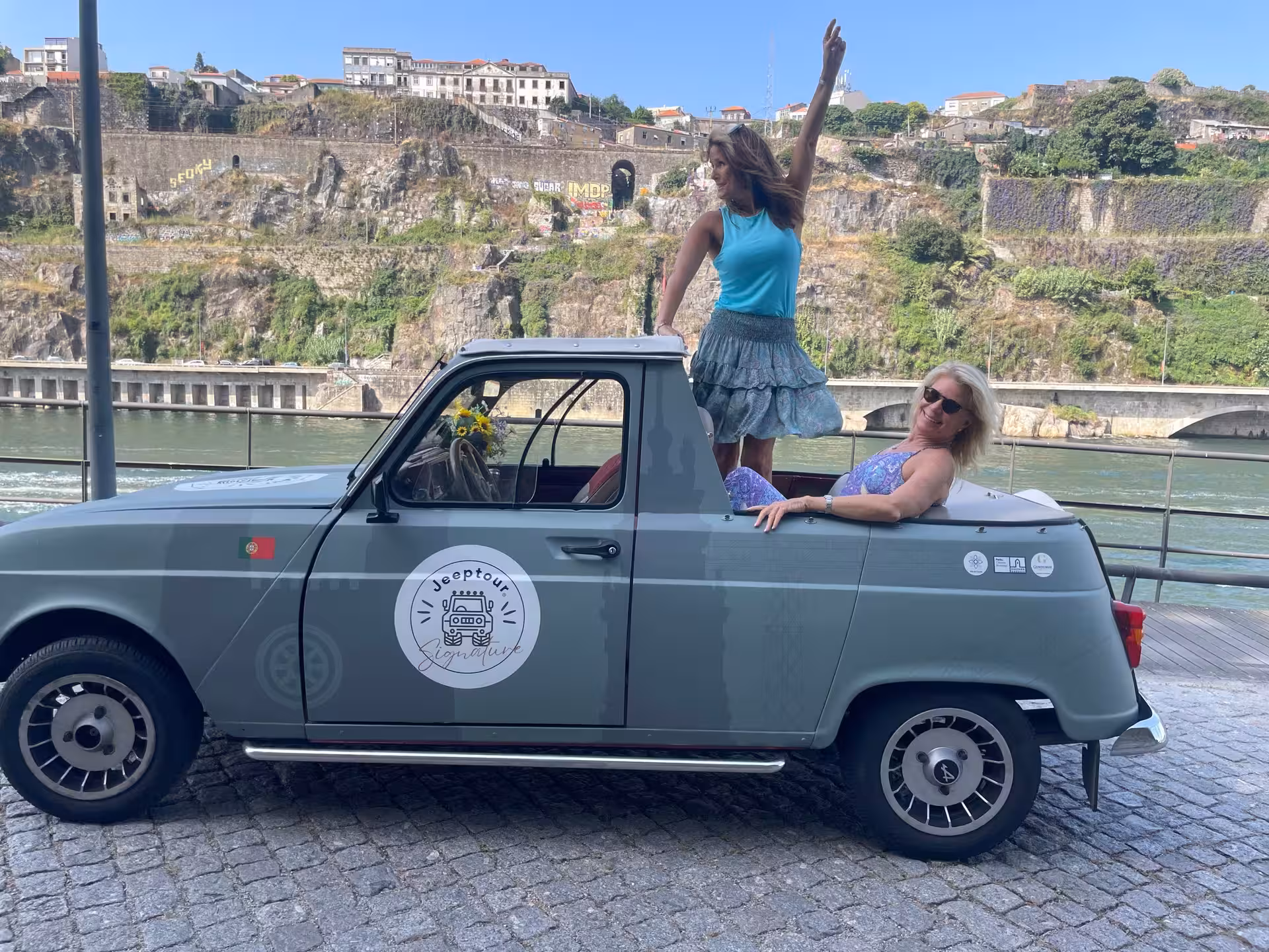 Guests riding a vintage convertible by the Douro River, Porto scenic viewpoint stop on city tour