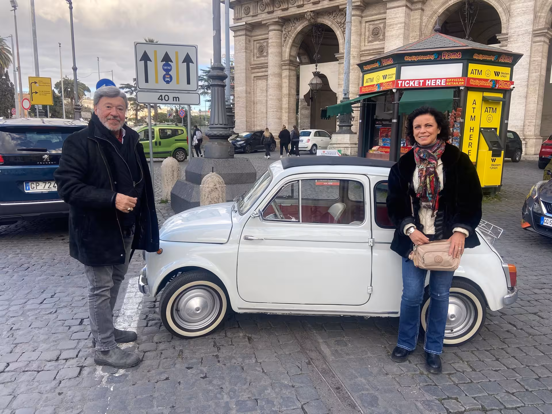 Tourists with a vintage Fiat 500 in front of a historic site on the Ancient Ostia Vintage Tour in Italy.