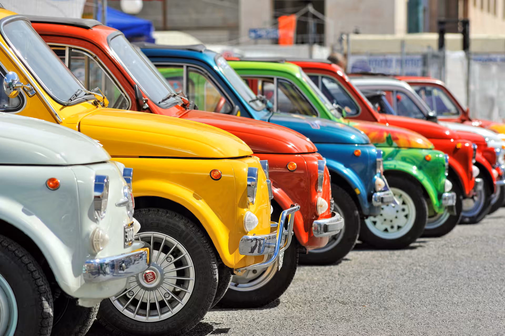 Colorful vintage Fiat 500 cars lined up for a scenic Chianti Classico wine tour in Tuscany.
