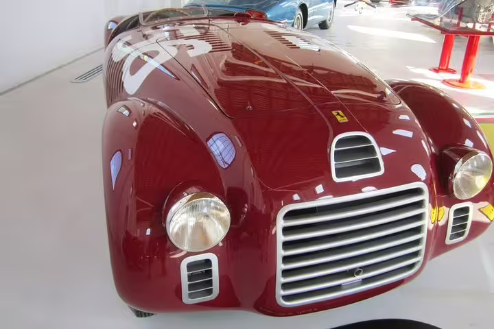 Vintage red Ferrari race car on display inside the Modena Ferrari Museum, a highlight of the private tour and tasting experience