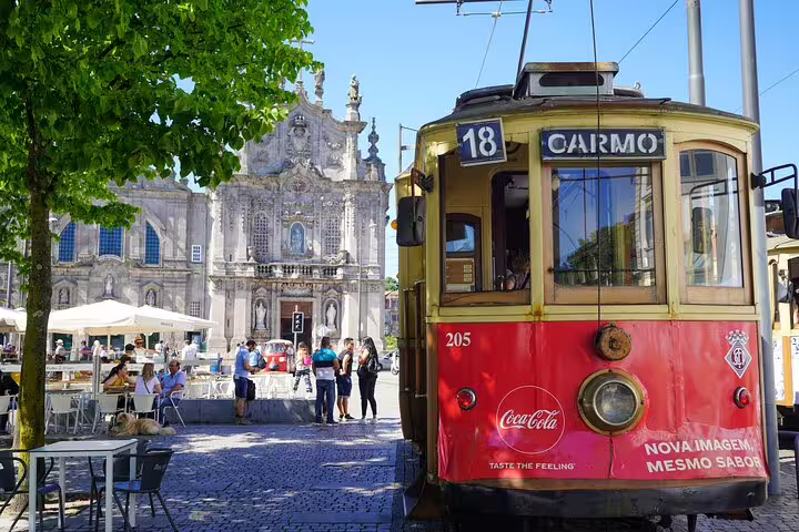 Vintage tram in Porto near Carmo Church, showcasing the charm of a private day trip from Lisbon with historic sights and local culture.