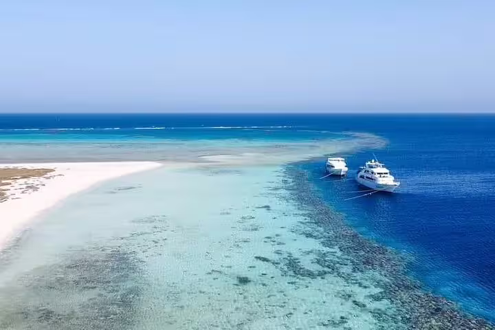 VIP boat anchored by Hamata Island reef and sandbar, Marsa Alam snorkeling day trip in crystal-clear Red Sea