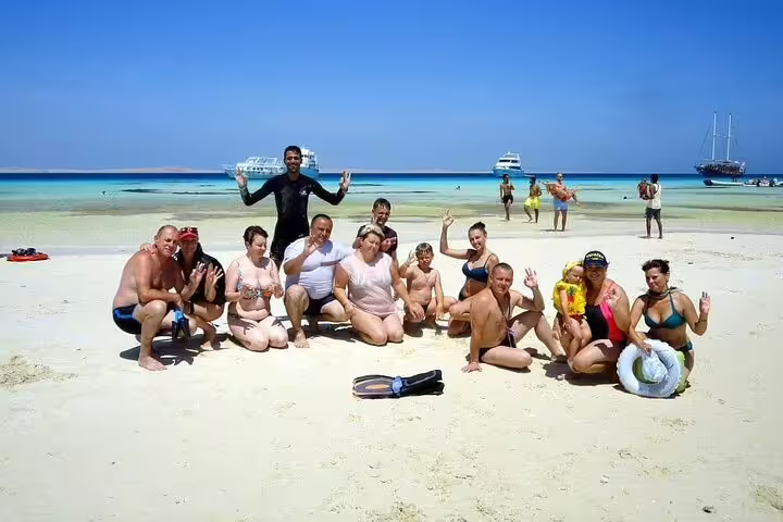 VIP boat snorkeling tour group relaxing on White Island beach, Sharm El Sheikh with Red Sea boats behind