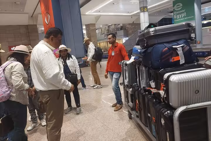 Travelers gather around luggage cart during VIP Cairo airport meet and assist service for smooth transfer.