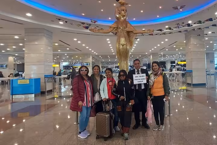 Group of travelers at Cairo Airport with VIP meet and assist service, posing by a golden statue in the terminal.