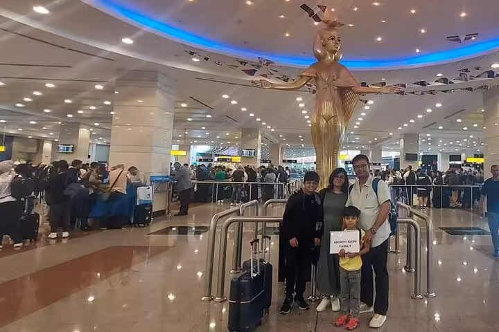 Travelers at Cairo International Airport enjoying VIP meet and assist services under the stunning golden statue.
