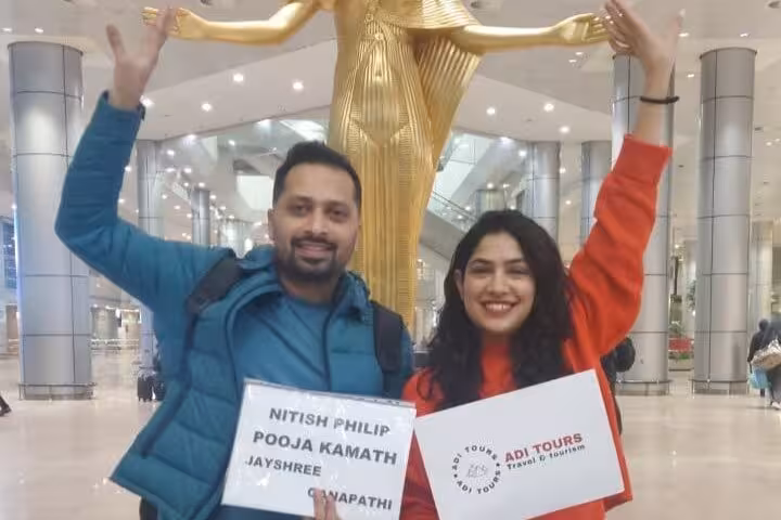 Smiling travelers holding signage for VIP Cairo airport meet and assist service inside modern terminal.