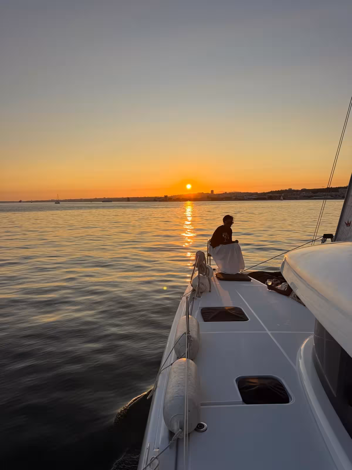 VIP catamaran private sunset and wine tour with guest relaxing on deck, golden hour sail along the coast