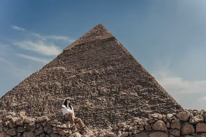Traveler resting by the Great Pyramid of Giza on a VIP all-inclusive tour with private guide and transfers