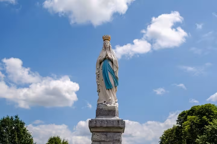 Statue of the Virgin Mary crowned under a clear blue sky in Lourdes, a highlight of the city walk tour.