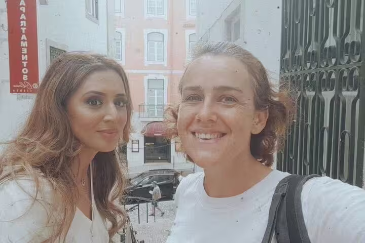 Two visitors pose on a picturesque Lisbon street, capturing moments from their walking tour.