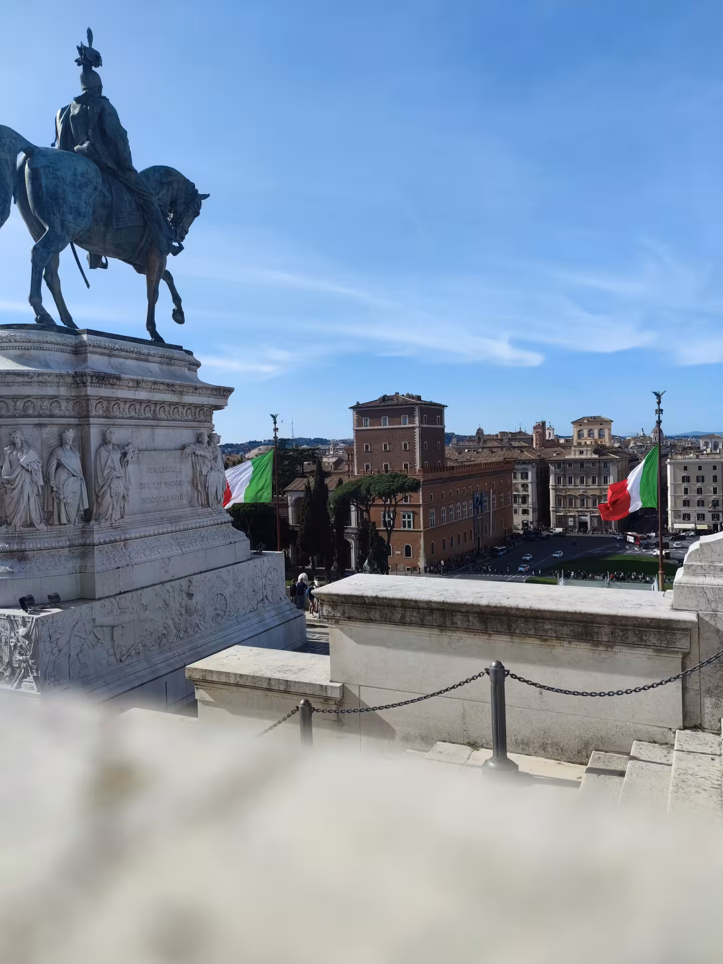 View of the Vittoriano monument in Rome with Italian flags and cityscape on a sunny day, ideal for cultural tours.