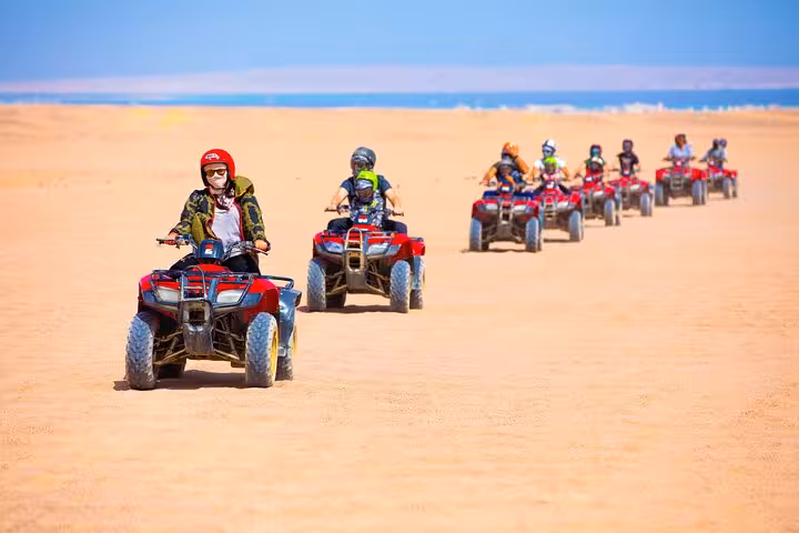Group riding quad bikes across desert dunes on Viva Safari tour with adventure, dinner and live show