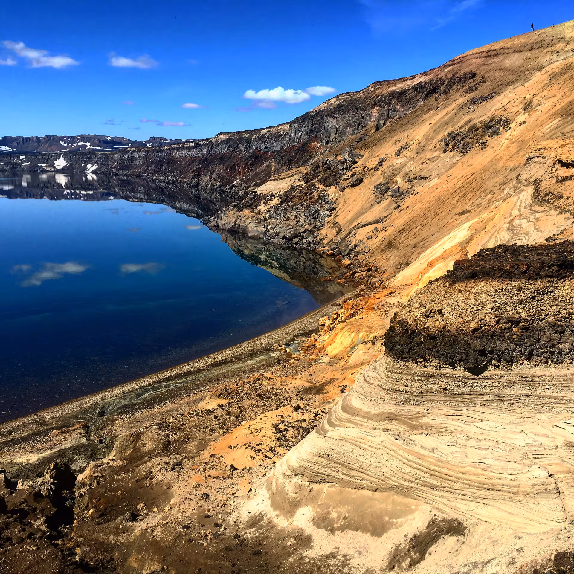 Striking volcanic landscape with vibrant rock formations and a serene lake, great for a photography day tour.